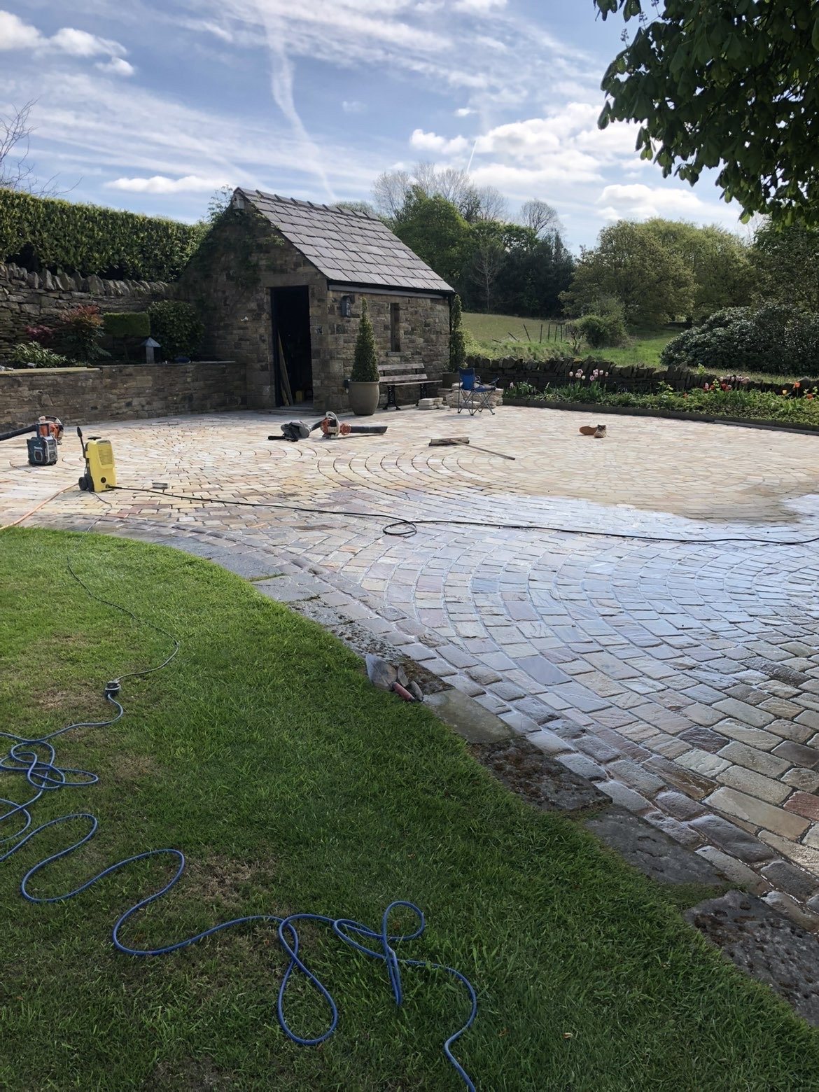 Finished sett-paved courtyard beside stone outbuilding